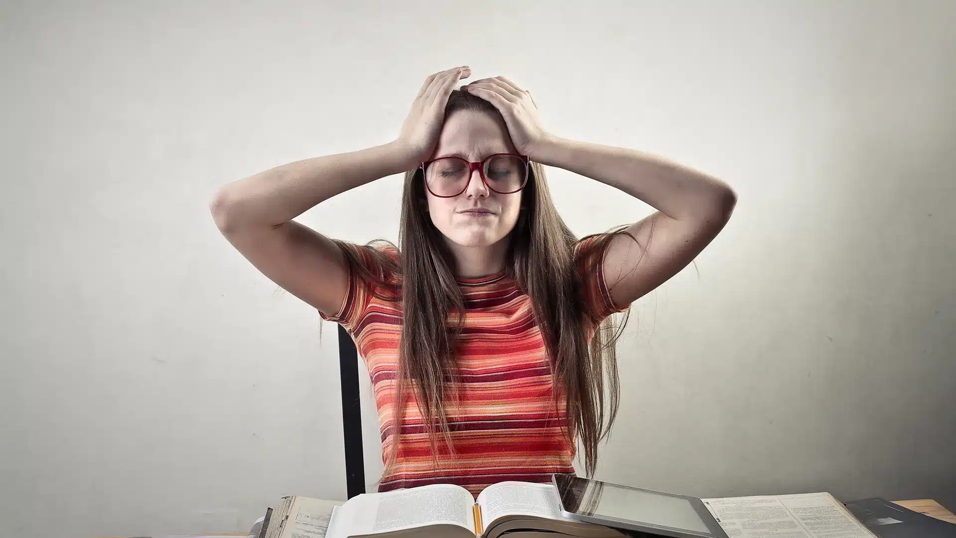 Garota cercada por livros desesperada por não conseguir estudar